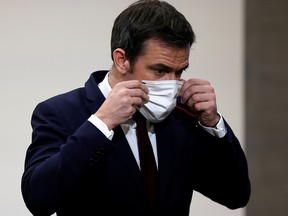 French Health Minister Olivier Veran puts on his mask after a press conference in Paris, January 14, 2021.