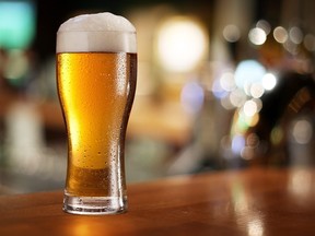 Glass of light beer on a dark pub.