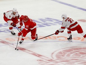 Red Wings right wing Filip Zadina (centre) skates with the puck defended by Hurricanes centre Jordan Staal (left) and right wing Andrei Svechnikov (right) during NHL action at Little Caesars Arena in Detroit, Jan 14, 2021.