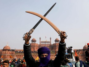 A farmer holds up a sword during a protest against farm laws introduced by the government, at the historic Red Fort in Delhi, India, Tuesday, Jan. 26, 2021.