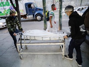 Employees of a funeral home move a stretcher with the body of a person who died from COVID-19, at the Iztapalapa neighbourhood in Mexico City, Jan. 19, 2021.