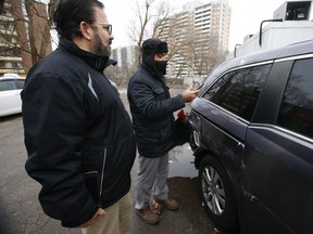 Sohail Chowdhry (R) takes pictures of his brother Mohammed Chowdhry's (L) minivan that was badly damaged a night earlier during a police takedown behind a Church's Chicken restaurant at Midland and Eglinton Aves. on Friday, Jan. 15, 2021.