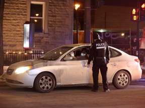 Police ticket a vehicle as they enforce a night curfew imposed by the Quebec government to help slow the spread of COVID-19, in Montreal, Saturday, Jan. 9, 2021.