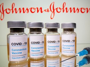 Vials with a sticker reading, "COVID-19 / Coronavirus vaccine / Injection only" and a medical syringe are seen in front of a displayed Johnson & Johnson logo in this illustration taken October 31, 2020.