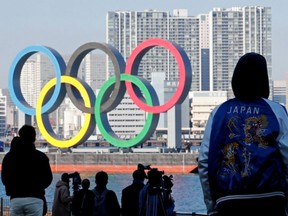 Bystanders watch as giant Olympic rings are reinstalled at Odaiba Marine Park, after they were temporarily taken down in August for maintenance amid the COVID-19 outbreak, in Tokyo, Dec. 1, 2020.