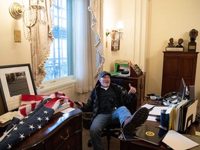 A supporter of President Donald Trump sits inside the office of Speaker of the House Nancy Pelosi as he protest inside the U.S. Capitol in Washington, January 6, 2021.