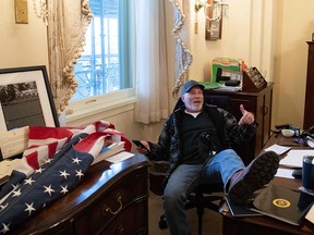 A supporter of President Donald Trump sits inside the office of Speaker of the House Nancy Pelosi as he protests inside the U.S. Capitol in Washington, Jan. 6, 2021.