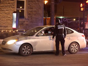 Police ticket a vehicle as they enforce a night curfew imposed by the Quebec government to help slow the spread of the coronavirus pandemic in Montreal January 9, 2021.