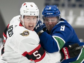 Senators defenceman Mike Reilly and Canucks forward J.T. Miller fight for the puck during their game on Monday. THE CANADIAN PRESS