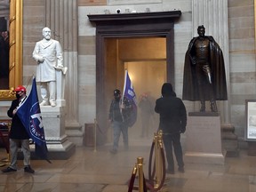 Supporters of President Donald Trump enter the U.S. Capitol’s Rotunda as tear gas smoke fills a corridor on January 6, 2021, in Washington. (SAUL LOEB/AFP via Getty Images)