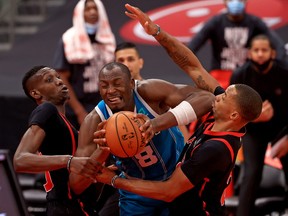 Chris Boucher (left) and Norman Powell surround Charlotte's Bismack Biyombo (centre) on Saturday.