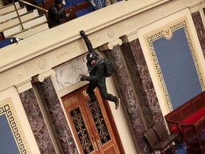 A protester is seen hanging from the balcony in the Senate Chamber on January 6, 2021 in Washington. (Win McNamee/Getty Images)