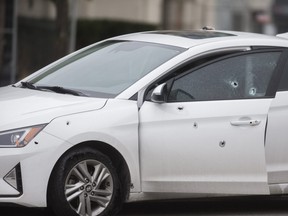 Police examine bullet holes in a car at the scene of a shooting just before 7 a.m. on New Year's Day at Princess Blvd. and Newfoundland Rd. on the CNE grounds. An adult female was taken to hospital with serious injuries.