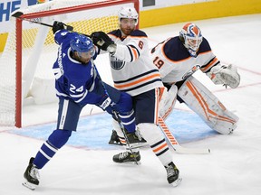 Oilers defenceman Adam Larsson (rights) tries to move Maple Leafs forward Wayne Simmonds from out in front of the Edmonton net during the first period last night at Scotiabank Arena.