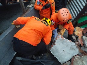 This handout photo taken and released on January 15, 2021 by Indonesia's National Disaster Agency shows rescuers looking for survivors trapped in a collapsed building in Mamuju, after a 6.2-magnitude earthquake rocked Sulawesi Island.