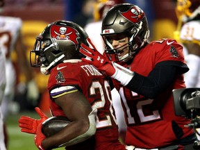 Buccaneers QB Tom Brady (right) congratulates running back Leonard Fournette (left) after a touchdown against Washington during NFL playoff action at FedExField in Landover, Md., Saturday, Jan. 9, 2021.