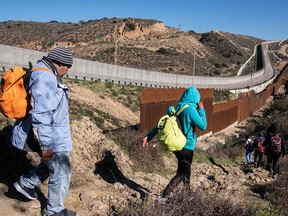 A group of Central American migrants look for a spot to cross the US-Mexico border fence from Tijuana, Mexico, into the U.S., on December 30, 2018.