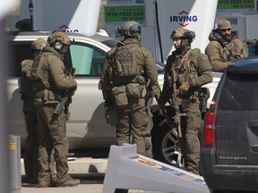 In this file photo taken on April 19, 2020, members of the RCMP tactical unit confer after the suspect in a deadly shooting rampage was neutralized at the Big Stop near Elmsdale, Nova Scotia.