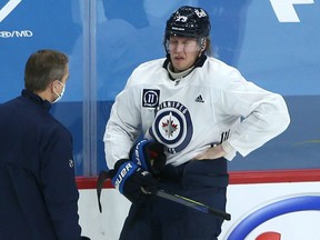 Patrik Laine (right) grabs his side and grimaces in pain while speaking to head coach Paul Maurice during a practice on Sunday. Lanie missed last night’s game against the Maple Leafs.