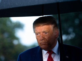 In this file photo US President Donald Trump holds an umbrella as he speaks to the media under the rain prior to departing from the South Lawn of the White House in Washington, DC, September 17, 2020.
