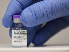 In this file photo taken on December 08, 2020 A member of staff poses with a phial of Pfizer-BioNTech Covid-19 vaccine at a vaccination health centre in Cardiff, South Wales' on December 8, 2020.