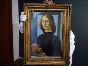 A worker at Sotheby's Auctions poses with Sandro Botticelli's "Young Man Holding a Roundel" during a preview. The painting sold on Thursday, Jan. 28, 2021, for $92.2 million, a world record for any work by an Italian artist, in the Manhattan borough of New York City, New York, U.S., January 22, 2021.