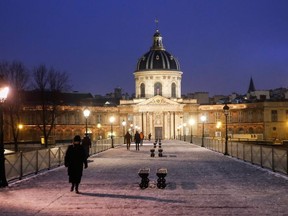People walk on the Pont des Arts covered with snow, during a nationwide curfew, from 6 p.m. to 6 a.m., due to restrictions against the spread of the coronavirus disease (COVID-19), in Paris, France, January 16, 2021.