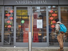 A man stands in front of the Nordstrom store, closed for in-store shopping in downtown Toronto, on Nov. 23, 2020.