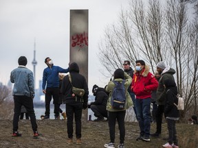 People gather around a steel monolith that has been placed at Humber Bay Park East in Toronto, Ont. on Friday, Jan. 1, 2021.