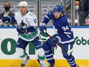 Auston Matthews of the Toronto Maple Leafs chases after the puck against Bo Horvat of the Vancouver Canucks during an NHL game at Scotiabank Arena on February 8, 2021 in Toronto, Ontario, Canada.