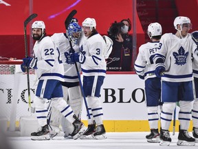 Zach Bogosian (No. 22) and Justin Holl (No. 3) of the Maple Leafs celebrate a 4-2 win alongside goalie Frederik Andersen over the Canadiens at the Bell Centre on Feb. 10, 2021 in Montreal, Canada.