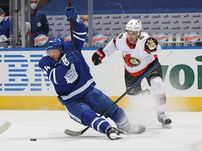 Senators' Artem Zub (right) is penalized for pulling down Morgan Rielly of the Maple Leafs during their game at Scotiabank Arena on Monday, Feb. 15, 2021 in Toronto.