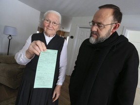 Martha Oppel, 85, displays her lockdown ticket while Pastor Henry Hildebrandt looks on.