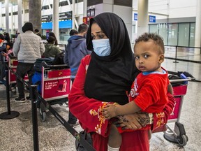 Fatim Ali holds her baby Motinsar, after arriving from Sudan at Terminal 1 at Toronto Pearson International airport on Feb. 22, 2021.
