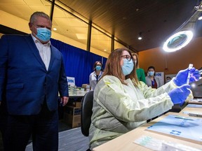 Ontario Premier Doug Ford watches a health-care worker prepare a Pfizer-BioNTech coronavirus disease (COVID-19) vaccine at The Michener Institute, in Toronto, on Jan. 4, 2021.