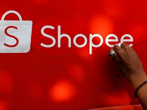 A worker wipes the door of a car with the sign of Shopee, an Indonesian e-commerce platform, in Jakarta February 5, 2021.
