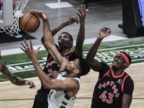 Bucks' Giannis Antetokounmpo (middle) reaches for a rebound under pressure from Raptors' Chris Boucher (25) and Pascal Siakam during the first quarter at Fiserv Forum in Milwaukee on Tuesday, Feb. 16, 2021.