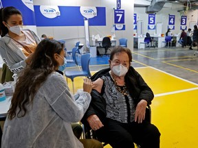 A health worker of the Maccabi Health vaccination centre administers a dose of the Pfizer-BioNtech COVID-19 coronavirus vaccine, inside the parking lot of the Givatayim mall in Israel's Mediterranean coastal city of Tel Aviv on January 26, 2021.