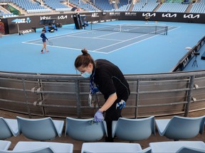 A worker cleans the seating areas on Court 3 during a warm up session at Melbourne Park in Melbourne on Feb. 4, 2021.