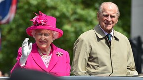 Queen Elizabeth and Prince Philip wave to guests from their car as they attend the Patron’s Lunch on the Mall, an event to mark her official 90th birthday in London, on June 12, 2016.