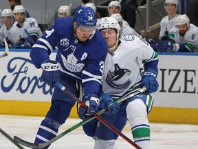 Maple Leafs forward Auston Matthews (left) battles for the puck against Brock Boeser (6) of the Canucks during NHL action at Scotiabank Arena in Toronto on Thursday, Feb 4, 2021.