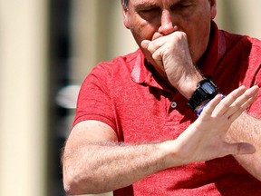 In this file photo, Brazilian President Jair Bolsonaro coughs as he speaks after joining his supporters who were taking part in a motorcade to protest against quarantine and social distancing measures to combat the new coronavirus outbreak in Brasilia on April 19, 2020.