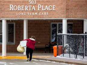 A woman carries items into Roberta Place, a long-term seniors care facility which is the site of a  COVID-19 outbreak, in Barrie January 18, 2021.