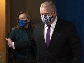 Ontario Premier Doug Ford opens the door as he and Health Minister Christine Elliott arrive for the daily briefing in Toronto on Monday, February 8, 2021.