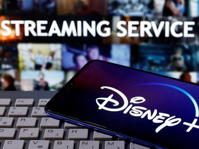 A smartphone with displayed "Disney" logo is seen on the keyboard in front of displayed "Streaming service" words in this illustration taken March 24, 2020.