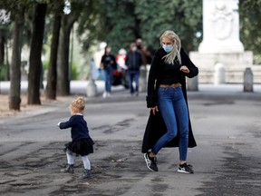 A woman wearing a protective mask plays with a child near Pincio Terrace, amid the outbreak of the coronavirus disease in Rome October 13, 2020.