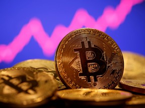 A representation of virtual currency Bitcoin is seen in front of a stock graph.