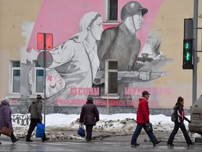 Locals cross a street in front of a building decorated with a Second World War themed mural in Oryol, Russia, on Feb. 5, 2019.