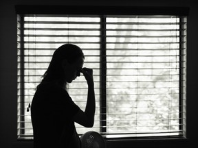 Tired woman standing next to bedroom window.
