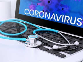 A stethoscope on a laptop keyboard with screen showing coronavirus